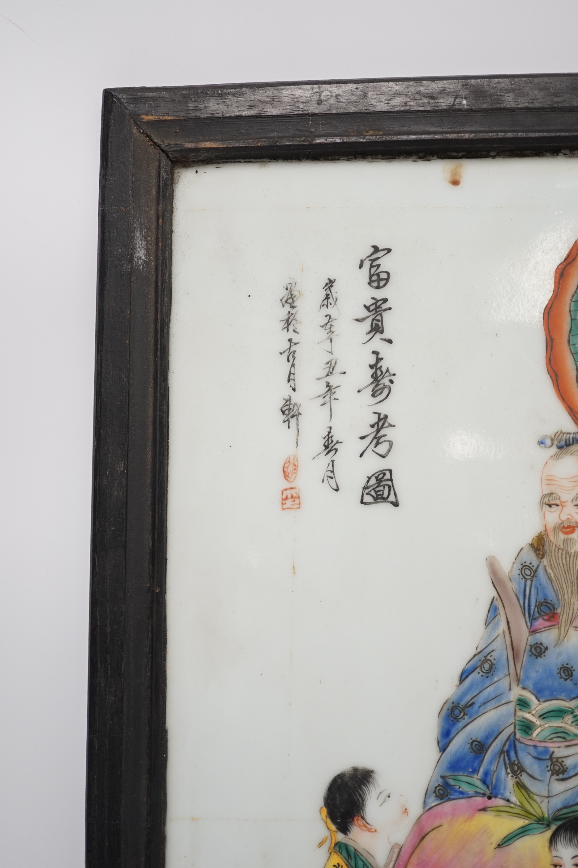 A framed Chinese porcelain plaque decorated with figures and calligraphy, overall 40cm x 29cm